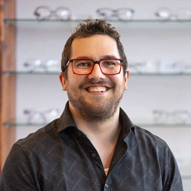 Male optometric technician smiling inside modern optometry clinic